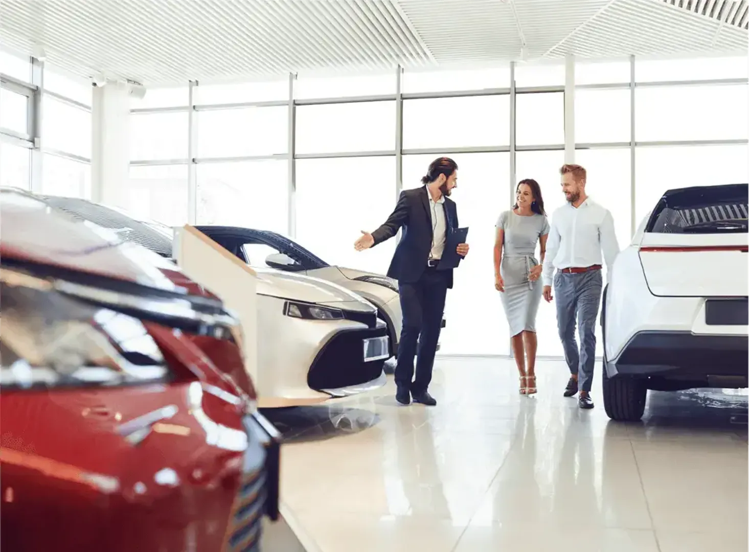Two people being shown different vehicles in a car showroom